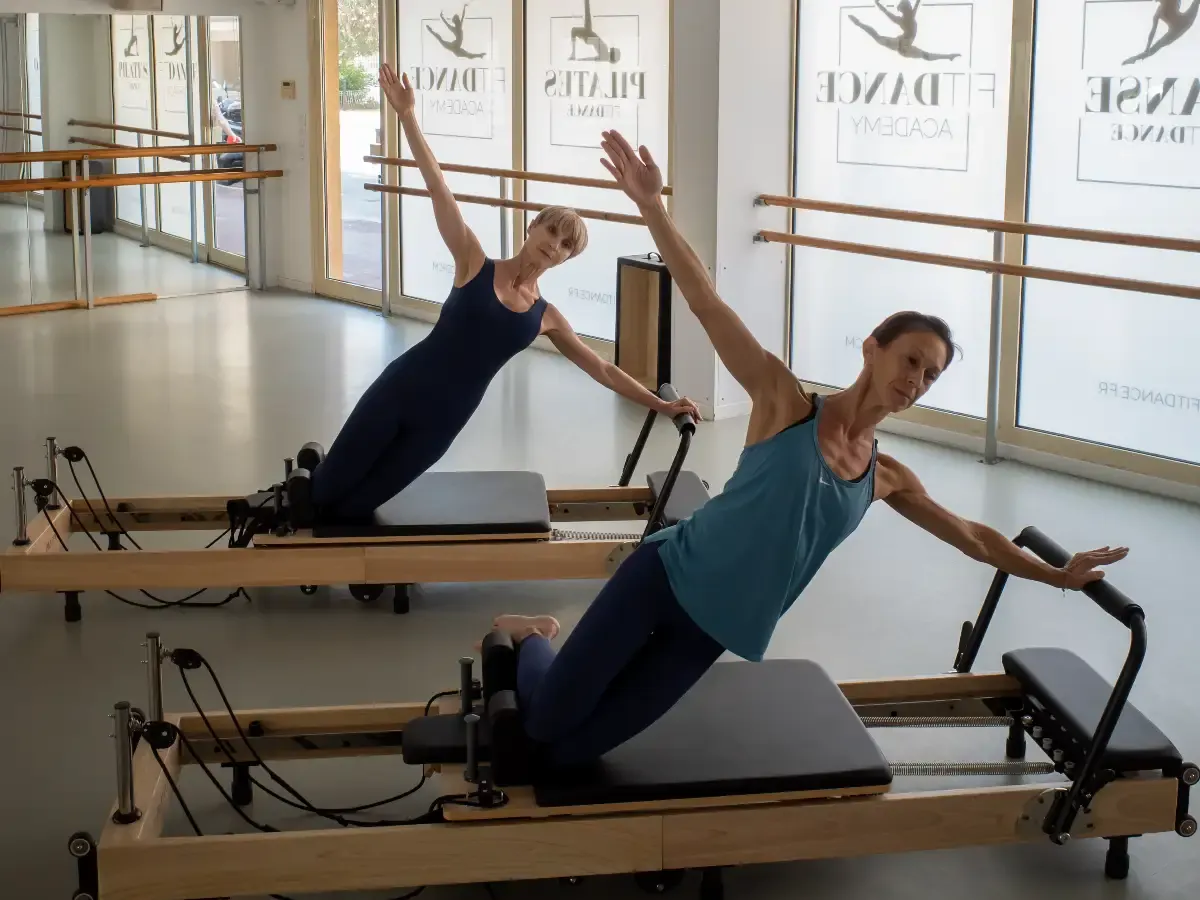 Séance de Pilates Reformer dans le studio Fitdance, devant les vitrines habillées aux logos Fitdance Academy, Pilates et Danse