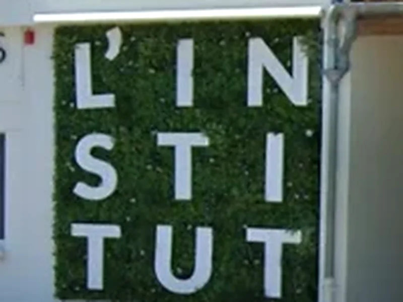 Enseigne de L'Institut Beauté & Soins à Cadillac-en-Fronsadais : le mot L'INSTITUT en grandes lettres blanches sur un mur végétal